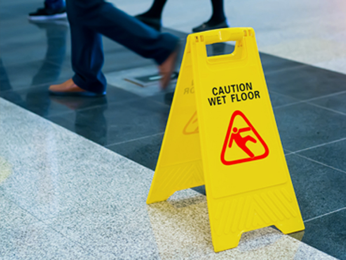 Caution Wet Floor sign on tile floor with people walking past